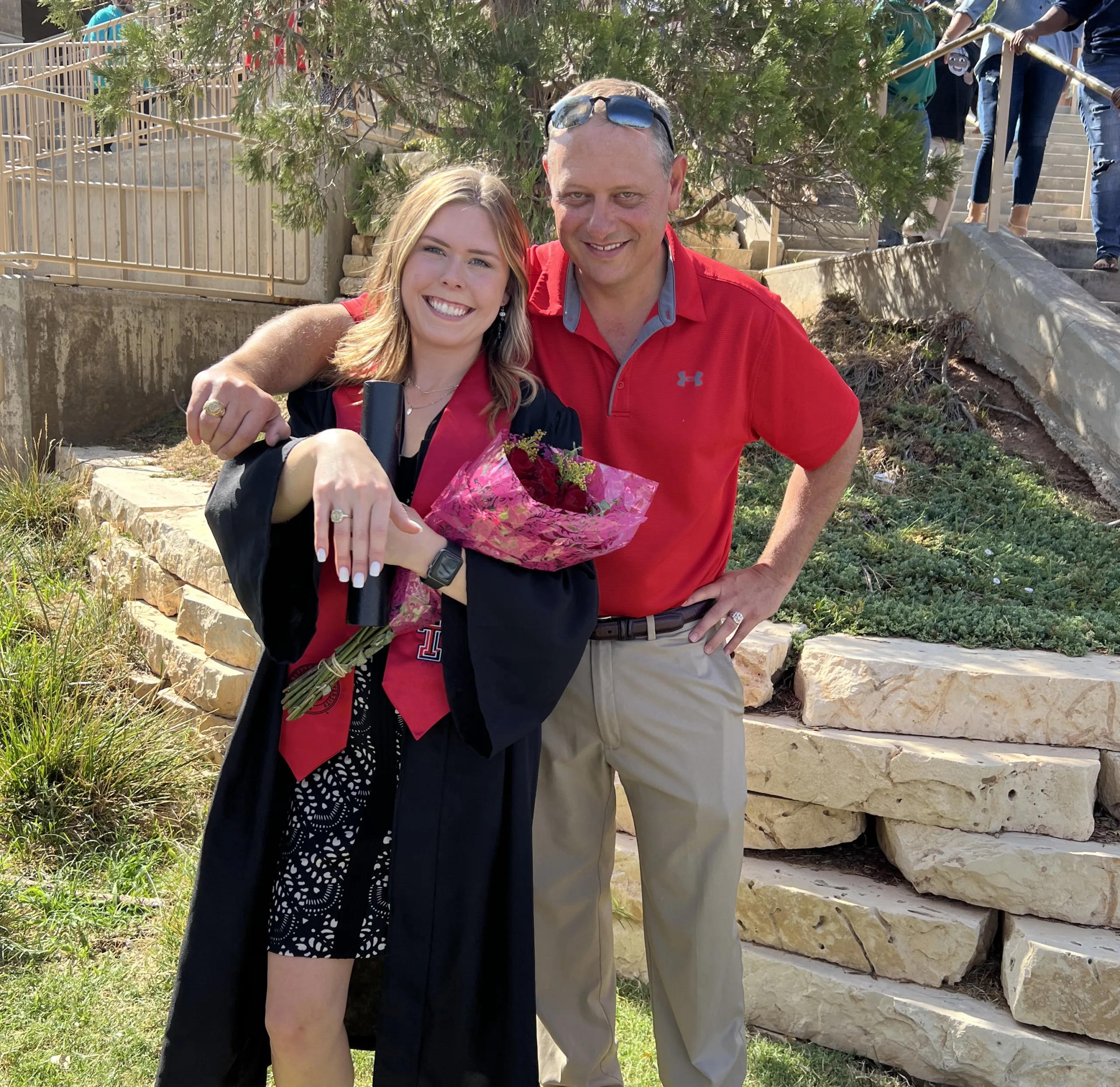 Graduate with diploma and relative celebrating outdoors.